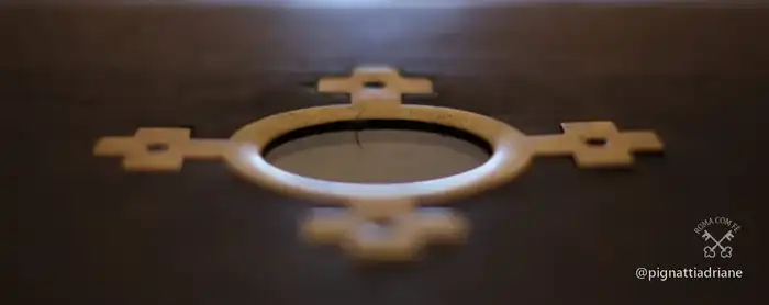 Uma das cruzes de bronze sobre o visor que protege o mármore original.